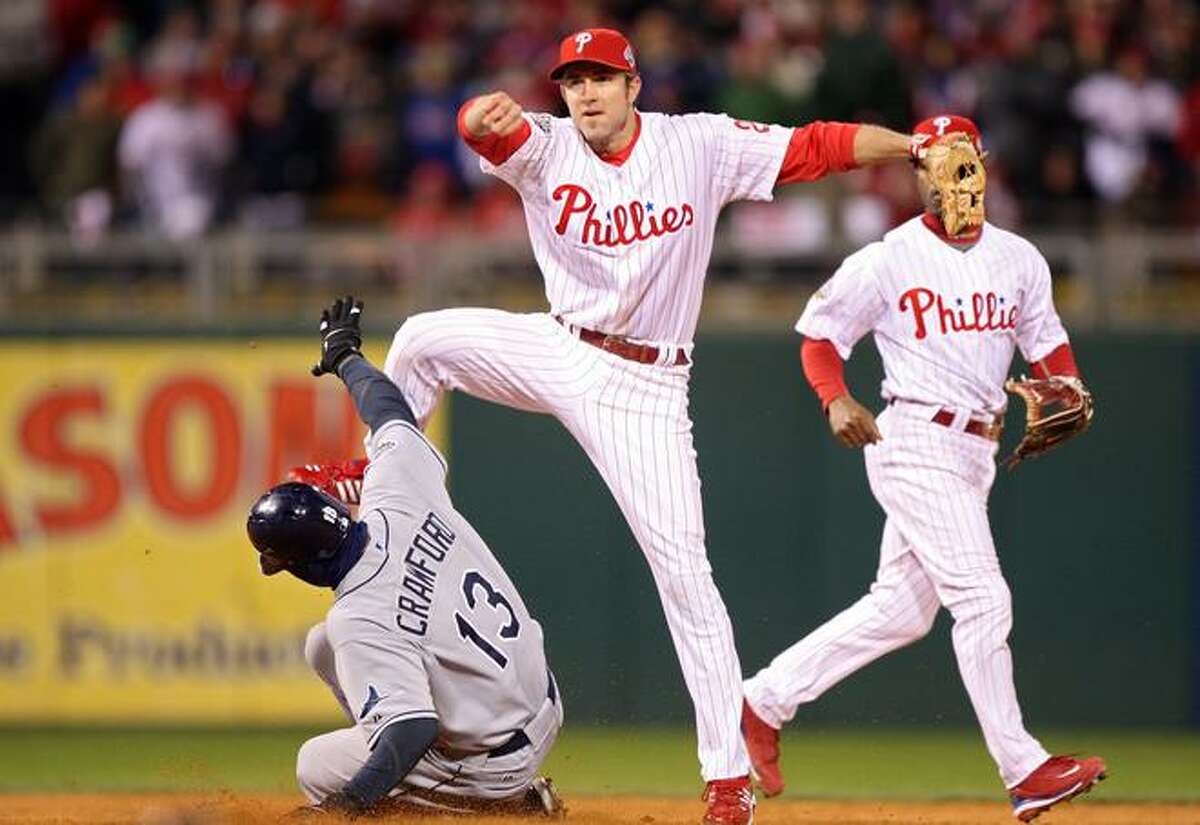 Phillies second baseman Chase Utley turns a double play over the sliding Carl Crawford of the Tampa Bay Rays Wednesday night as Philadelphia won its first World Series since 1980.