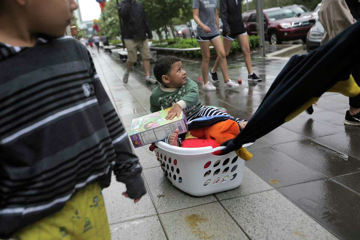 Nathan Gamez, 2, is pulled by his dad, Carlos Herrara after picking up supplies from the George R. Brown Convention Center in Houston as Tropical Storm Harvey inches its way through the area on Tuesday, Aug. 29, 2017.
