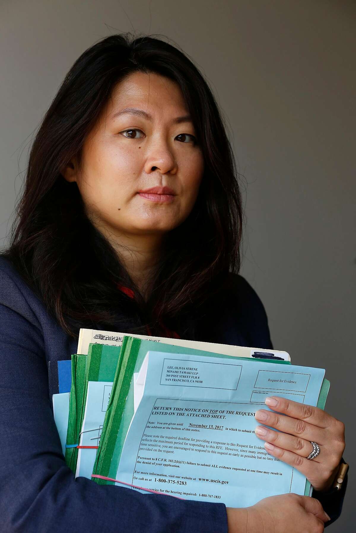 Olivia Lee, senior associate Minami Tamaki LLP, holds "Requests for Evidence" from immigration officials for some of her clients cases as she stands for a portrait in her office on Monday, August 28, 2017 in San Francisco, Calif.