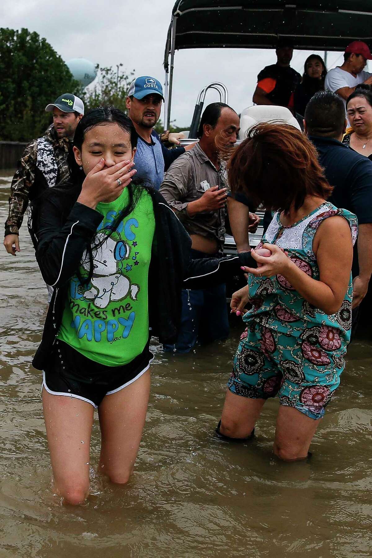Stephanie Vu, left, reacts after being rescued after falling in deep water as she evacuates with her parents from the Savannah Estates neighborhood as Addicks Reservoir nears capacity Tuesday, Aug. 29, 2017 in Houston.