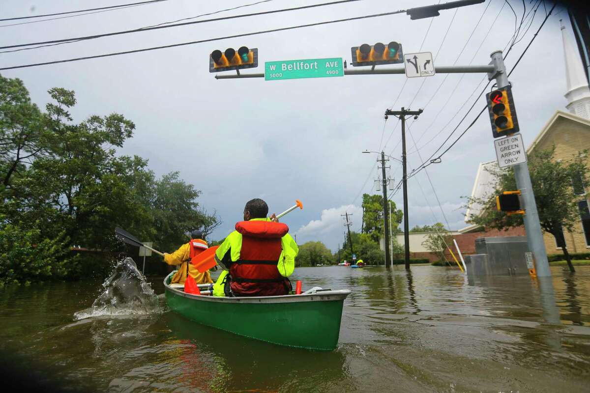 Houston fire fighters use a borrowed canoe to search for evacuees during extreme flooding in Meyerland, Sunday, Aug. 27, 2017, in Houston. (Mark Mulligan / Houston Chronicle)