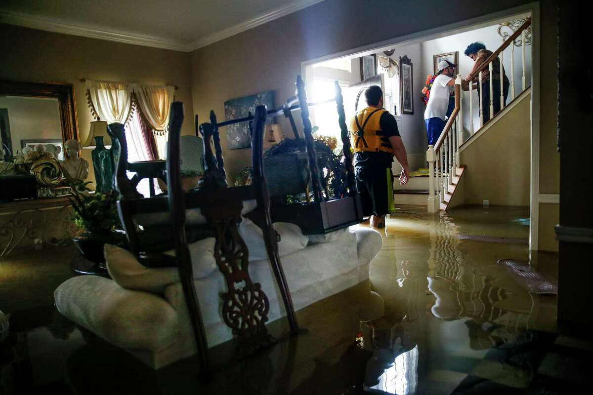 Chris Gutierrez, second from right, helps his grandmother, Edelmira Gutierrez, down the stairs of their flooded house and into a waiting fire department truck as Addicks Reservoir surpasses capacity due to near constant rain from Tropical Storm Harvey Tuesday, Aug. 29, 2017 in Houston.
