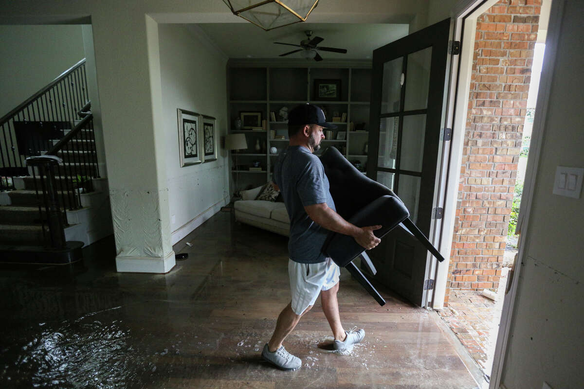Woodforest resident Thomas Cox removes a chair from his flooded Woodforest home on Tuesday, Aug. 29, 2017. (Michael Minasi / Chronicle)