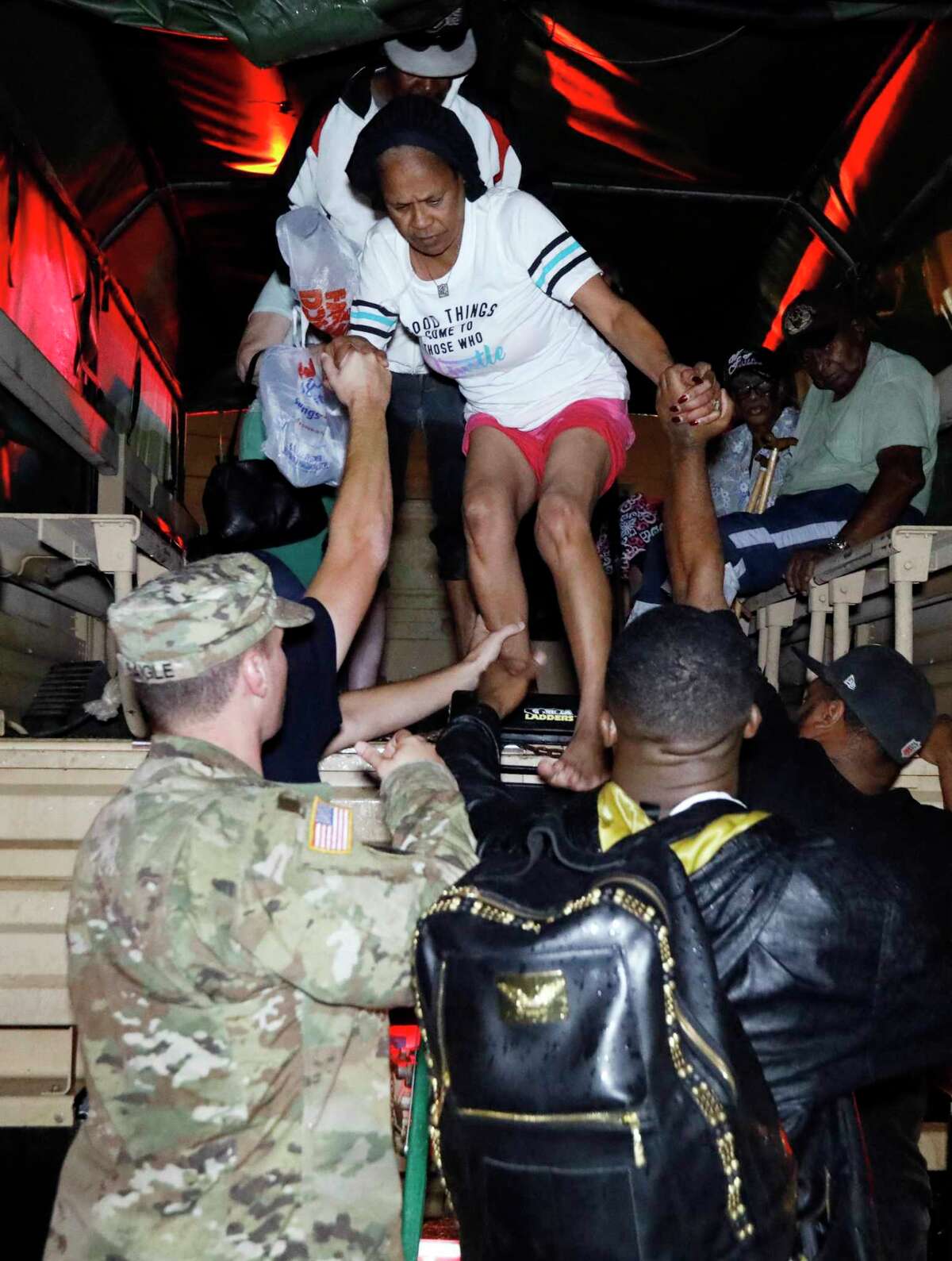 Lake Charles rescue personnel help residents exit from the back of a vehicle late Monday night, Aug. 28, 2017, in Lake Charles, La., after flooding from Harvey's almost constant rain over the last two days overcame the city's drainage system, flooding several subdivisions and necessitating home rescues. (AP Photo/Rogelio V. Solis)