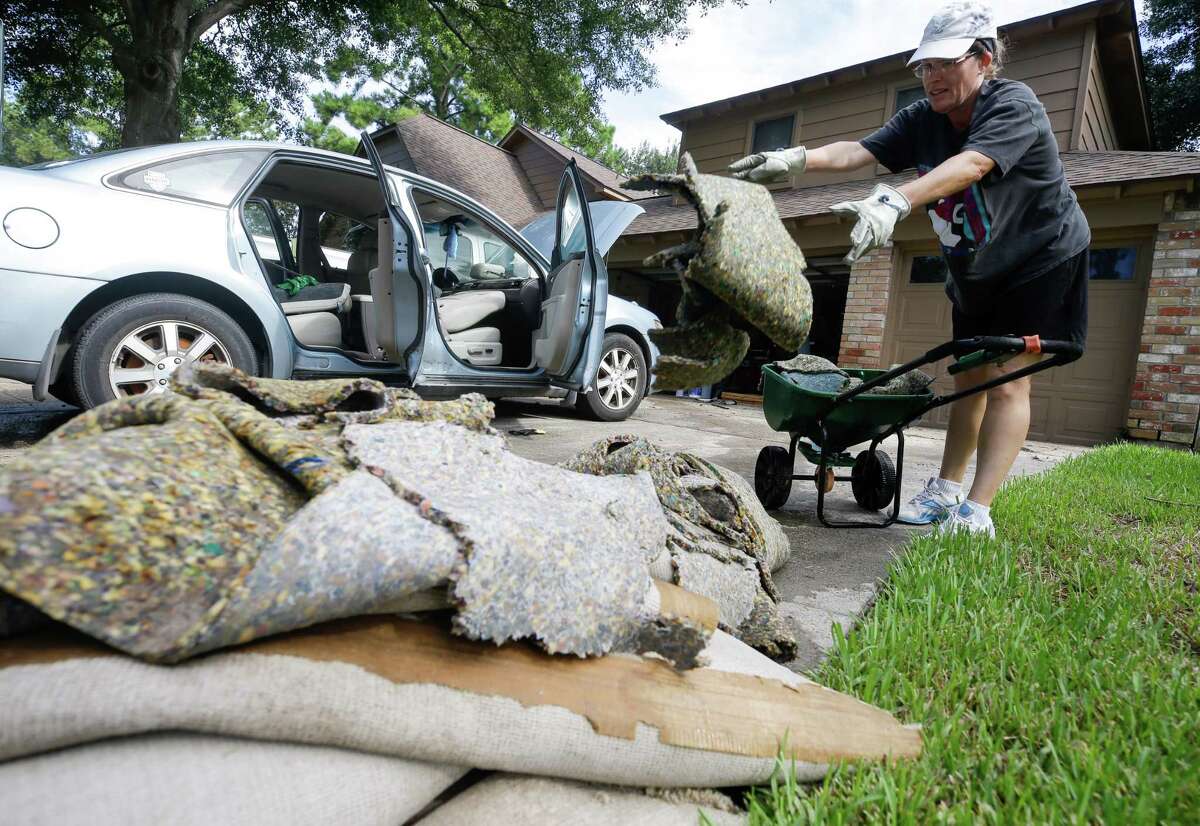 Susan Henney tosses wet carpet as she helps her neighbors clean up from flooding in the Lakewood Forest subdivision Wednesday, August 30, 2017 in Houston. Much of the Houston area was flooded in the aftermath of Hurricane Harvey.
