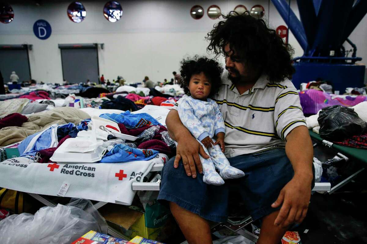 Edgar Molina holds his one-year-old daughter, Miracle Marie Molina, on a cot at the George R. Brown Convention Center where nearly 10,000 people are taking shelter after Tropical Storm Harvey Wednesday, Aug. 30, 2017 in Houston. Molina and his daughter have been at the shelter since Sunday.