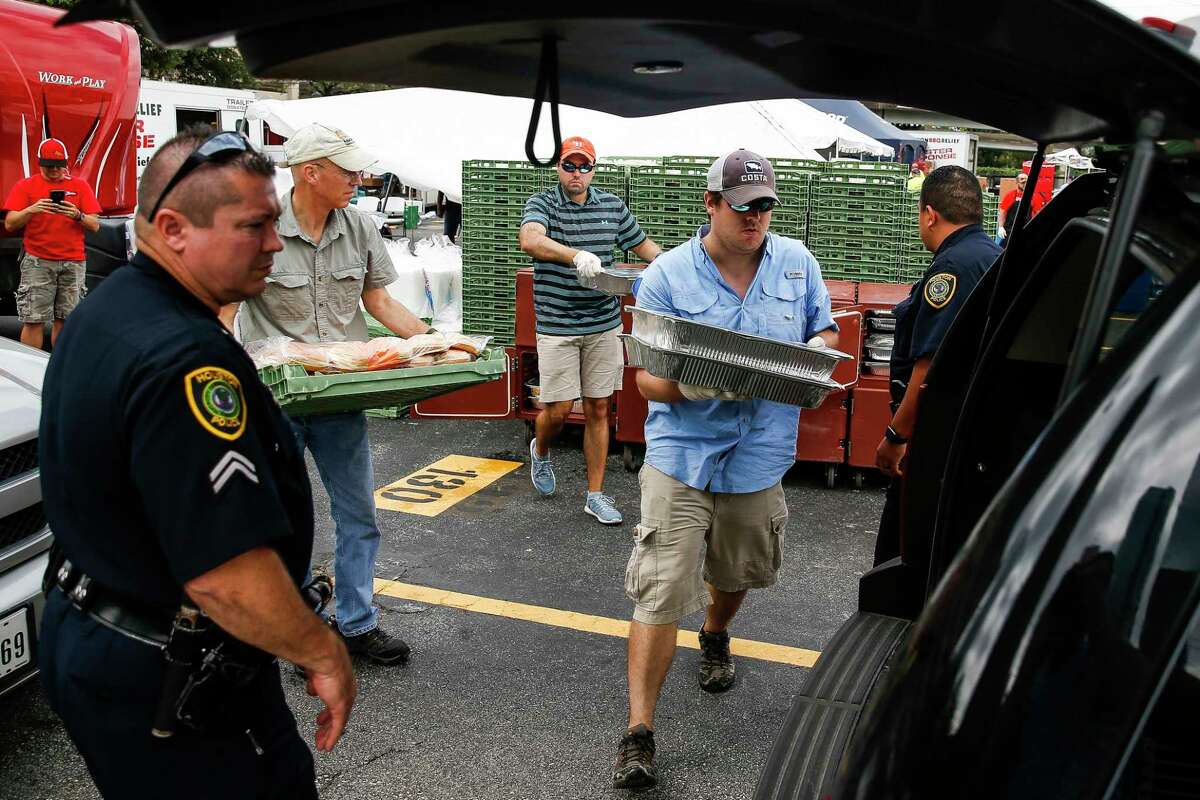 Operation BBQ Relief volunteer Brandon Reyes packs barbecue into the back of a police car for delivery in Houston. The volunteer operation aims cook meals that will feed at least half a million people over the course of two weeks as part of the organization's Houston deployment.