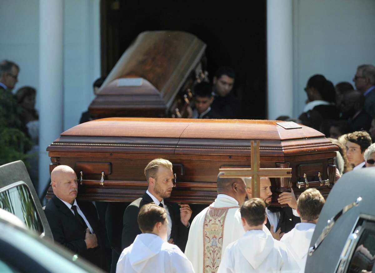 Caskets for Caroline, Loretta and Steven Dym are carried by pallbearers at the funeral mass.