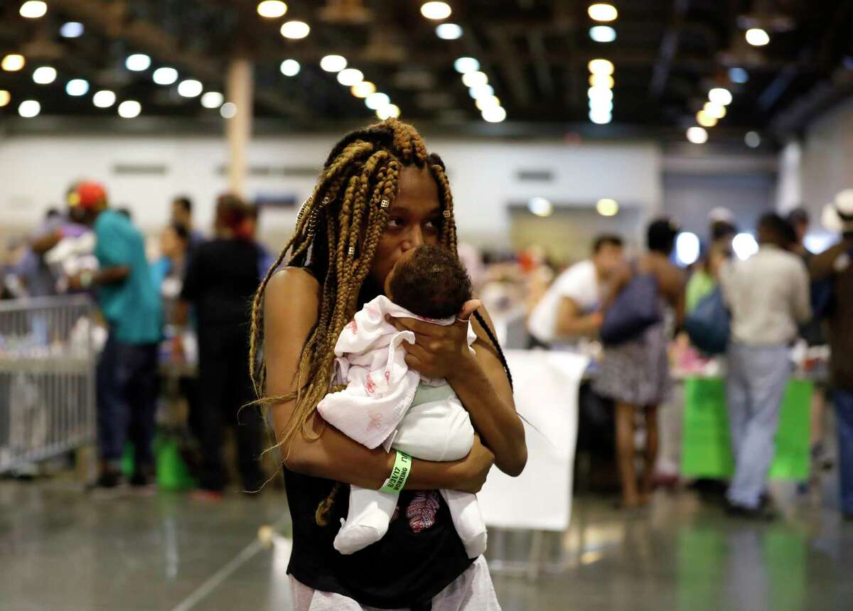Shaqualia Watkins comforts her one-month-old daughter, Kamarii, as she and other evacuees visit the area of NRG Center, where the goods, toys, snacks and clothing where being distributed for the 2500 people sheltering there, who were affected by Tropical Storm Harvey, Wednesday, Aug. 30, 2017, in Houston.