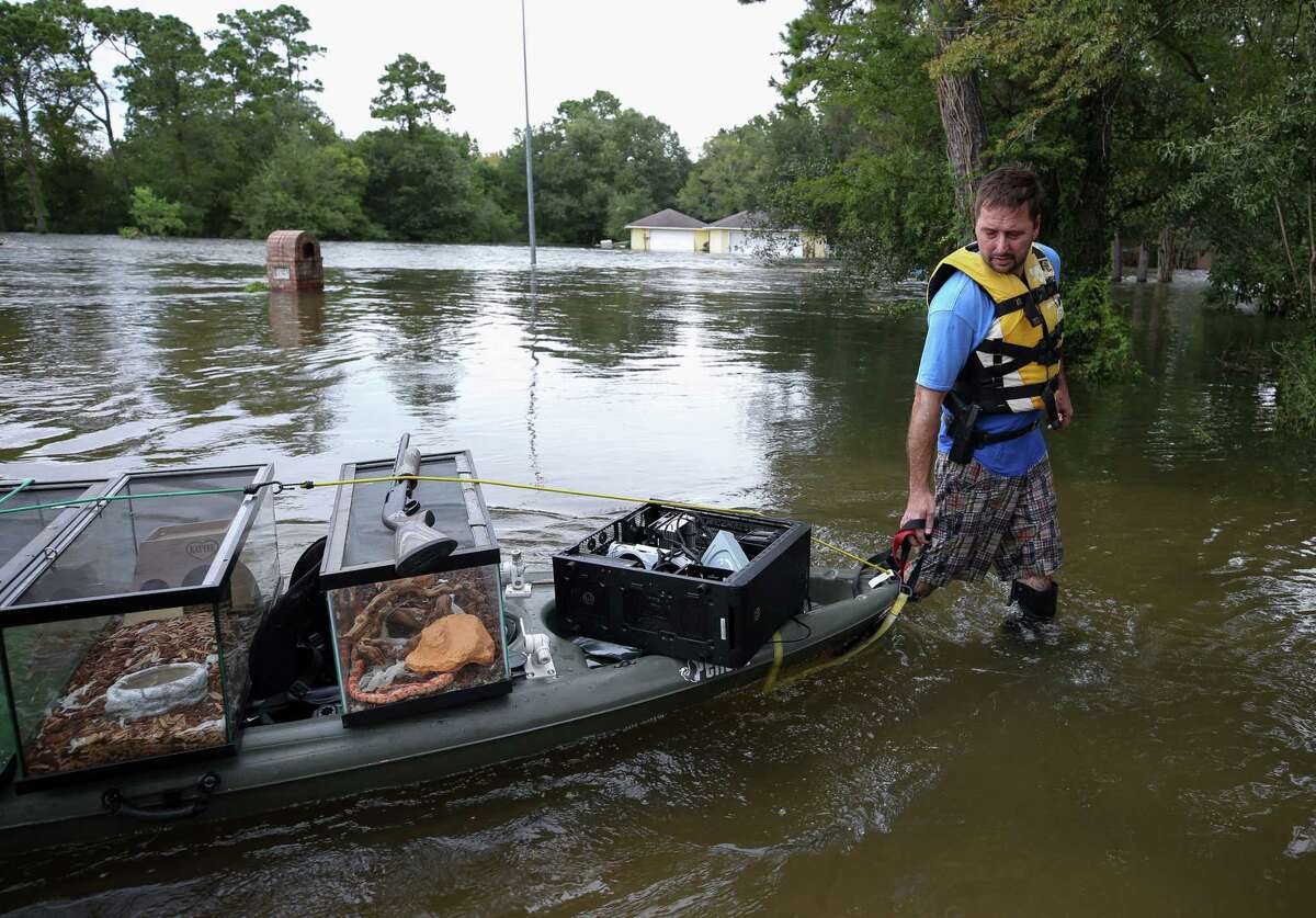Alen Pogue drags a kayak carrying three pet snakes, leopard gecko, and firearms after returning from his flooded home on Forrest Hollow Drive Wednesday, Aug. 30, 2017, in Baytown, Texas.