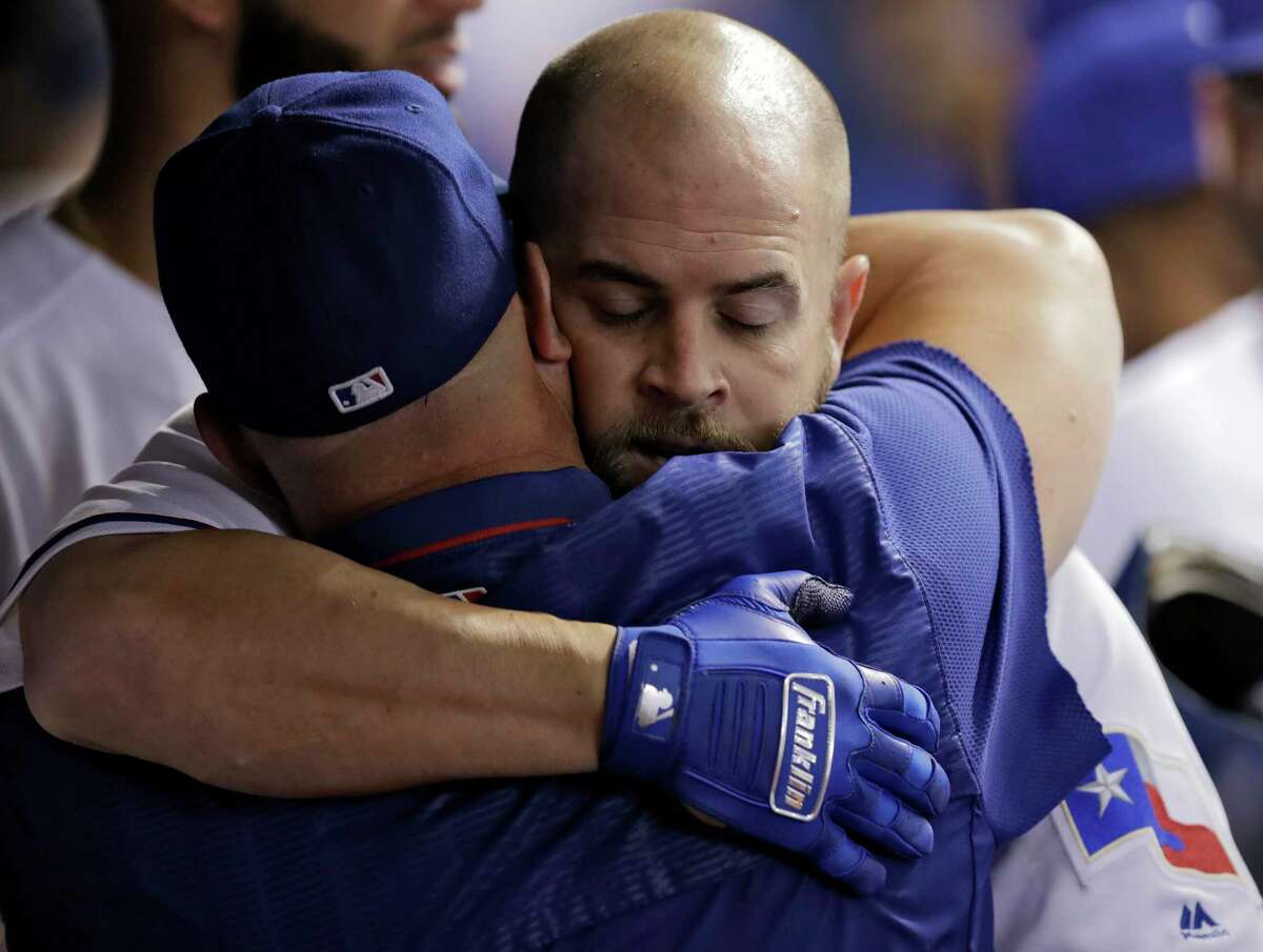 Texas Rangers' Mike Napoli, right, gets hugs in the dugout after his three-run home run off Houston Astros starting pitcher Dallas Keuchel during the fourth inning of a baseball game Wednesday, Aug. 30, 2017, in St. Petersburg, Fla. The Astros moved their three-game home series against the Rangers to St. Petersburg after being displaced by Hurricane Harvey. (AP Photo/Chris O'Meara)