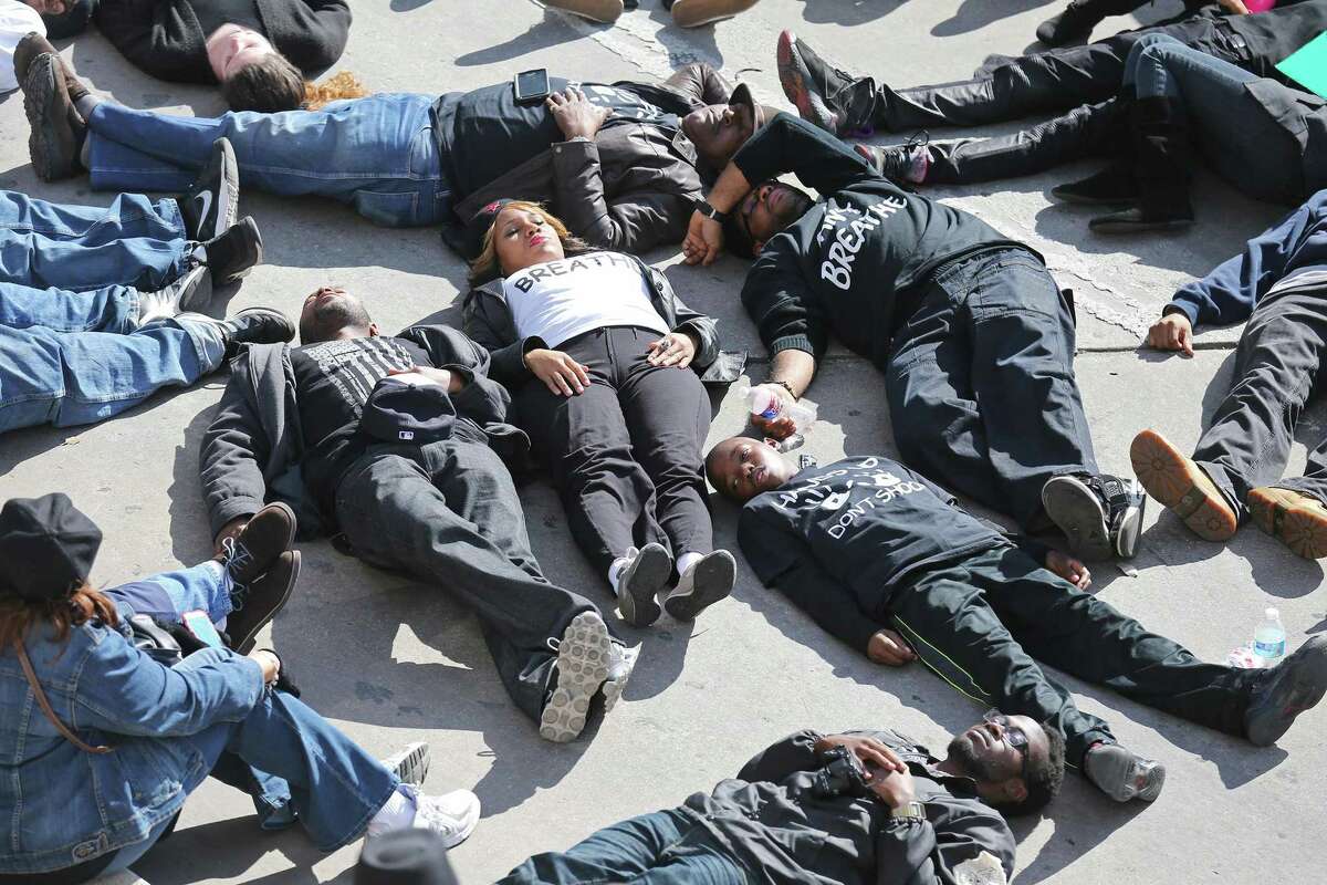 Protesters take part in a "die-in" , Saturday Dec. 20, 2014 at Rivercenter Mall, during a march through downtown protesting the deaths of Michael Brown, Eric Garner, Tamir Rice, Marquise Jones and others by police. About 200 people took part in the march.