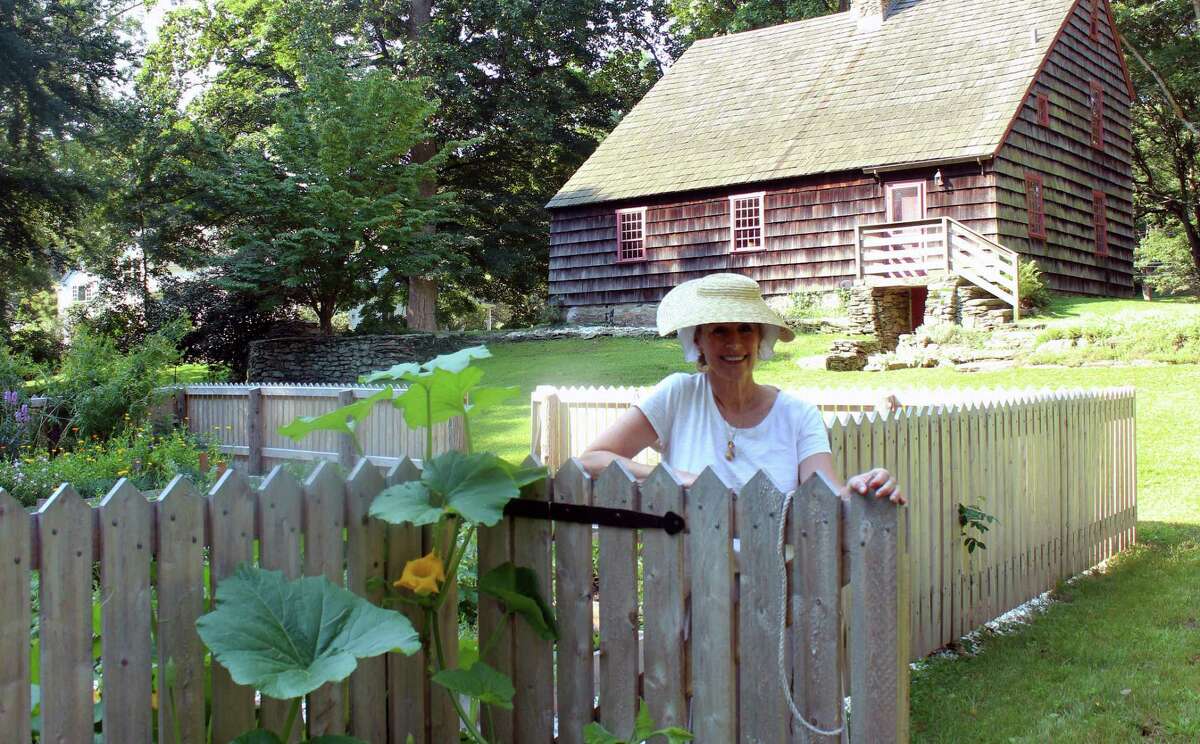 Whitney Vose, a member of the Fairfield Garden Club, and docent for the Colonial Kitchen Garden at the Ogden House, stands at the gate to the garden, where plants that would have been grown by colonial women are cultivated.