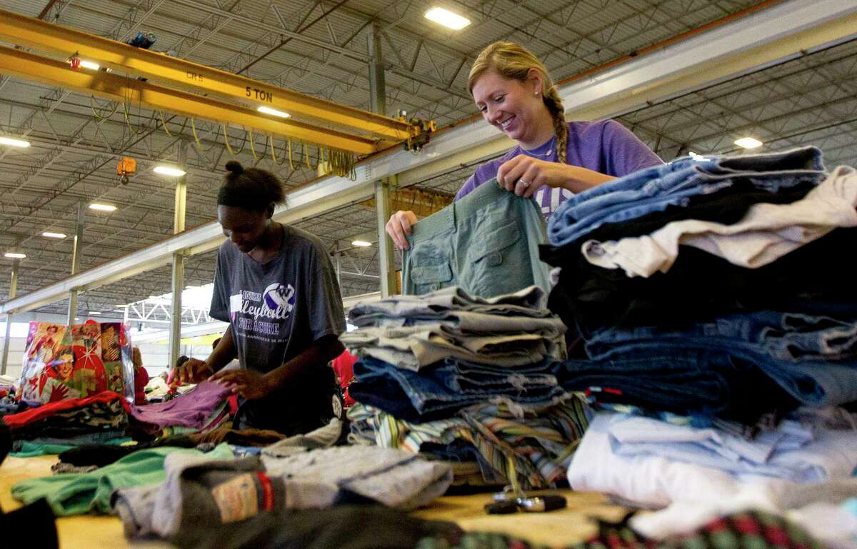 Willis head volleyball coach Megan Storms, right, shares a laugh with player De'Janae Gilmore as they sort and stack donated clothes at Falcon Steel's warehouse, Wednesday, Aug. 30, 2017, in Conroe. The company donated the space to serve as a central drop off location for donated supplies to help Montgomery County residents affect by Toprical Storm Harvey.