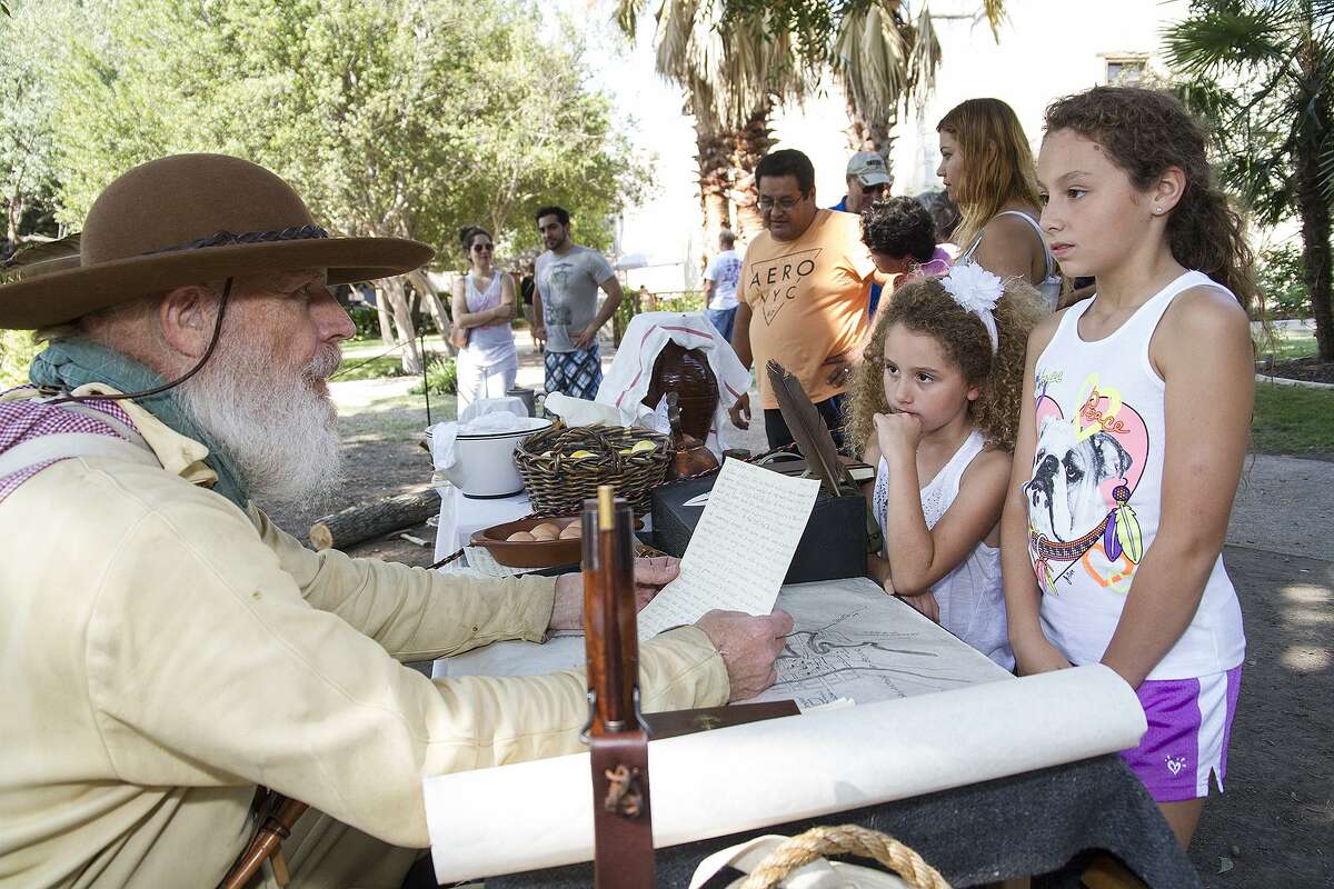 Seth Thomas reads a letter to sisters Valentina Miller, 6, and Natalie Miller, 9, (far right) as part of Fall at the Alamo, an annual interactive living history event with Alamo living history staff and volunteers, Oct. 10, 2015.
