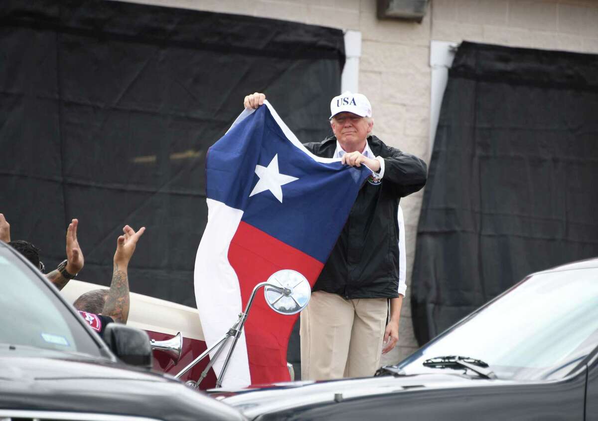 TOPSHOT - US President Donald Trump holds the state flag of Texas outside of the Annaville Fire House after attending a briefing on Hurricane Harvey in Corpus Christi, Texas on August 29, 2017. President Donald Trump flew into storm-ravaged Texas Tuesday in a show of solidarity and leadership in the face of the deadly devastation wrought by Harvey -- as the battered US Gulf Coast braces for even more torrential rain. / AFP PHOTO / JIM WATSONJIM WATSON/AFP/Getty Images