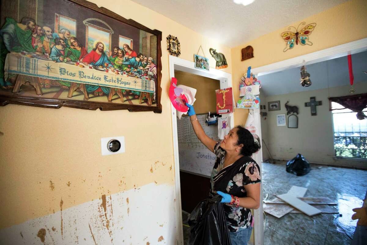 Alma Castanda pulls her children’s artwork off the walls as she cleans up her flood-damaged home in the Verde Forest subdivision days after Hurricane Harvey.
