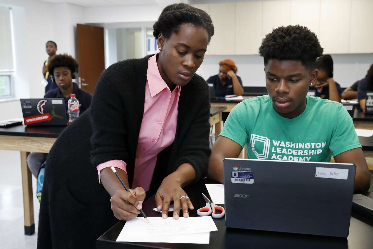 Britney Wray, a math teacher at Washington Leadership Academy, helps sophomore Kevin Baker, 15, with a math problem during class in Washington, Wednesday, Aug. 23, 2017. Students took diagnostic tests using special software. As they solved math problems on their laptops, the system diagnosed their proficiency levels in real time, part of "personalized learning." This approach uses software, data and constant monitoring of student progress to adapt teaching to each child's strengths, weaknesses, interests and goals and enable them to master topics at their own speed. (AP Photo/Jacquelyn Martin)