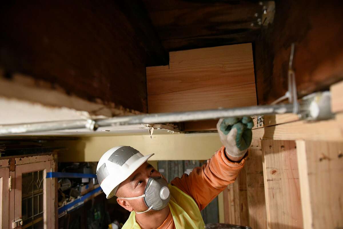 Construction worker Yuen Liang attaches angle straps to the top plate of a floor joist as SGDM contractors retrofit a mixed residential and commercial building in San Francisco, Calif., on Thursday August 31, 2017. Property owners in San Francisco are scrambling to retrofit their buildings as a new deadline looms for bringing buildings into compliance with the earthquake safety focused "soft story" ordinance.