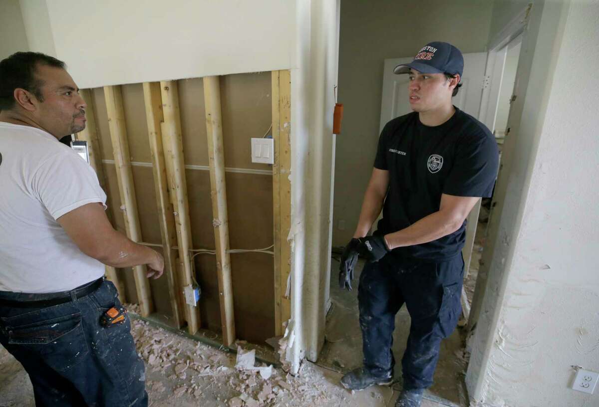 Jesse Morales, left, helps his son, Jordan Morales, a Houston firefighter with Station 9, clean up his flooded home Friday, Sept. 1, 2017, in Spring. He said about 5 feet of water flooded his home in the aftermath of Hurricane Harvey. He does not have flood insurance. ( Melissa Phillip / Houston Chronicle )