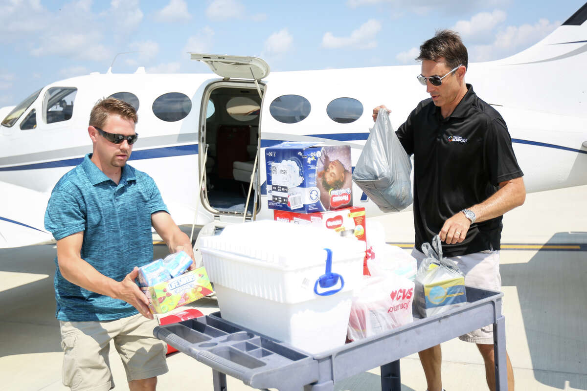 Volunteers Travis Forshee, left, and Robert Johnson, right, unload donations from a Cessna aircraft during Operation Air Drop on Friday at Conroe-North Houston Regional Airport.