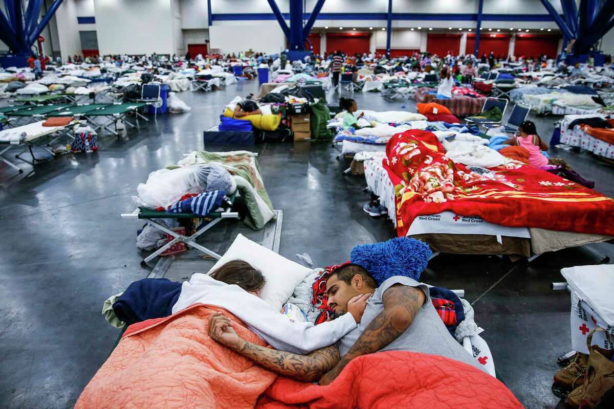 Tammy Dominguez, left, and her husband, Christopher Dominguez, sleep on cots at the George R. Brown Convention Center where nearly 10,000 people took shelter after Tropical Storm Harvey on Aug. 30.
