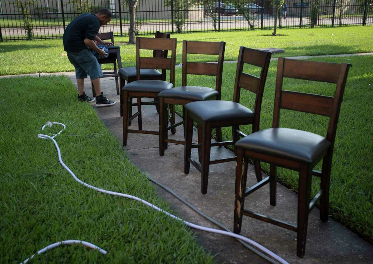 Byron Soto, 31, wipes off the dirt of flood waters from the dinning room chairs, Thursday, Aug. 31, 2017, in Houston. His family's apartment got flooded ruining their belongings as well as their two cars. ( Marie D. De Jesus / Houston Chronicle )