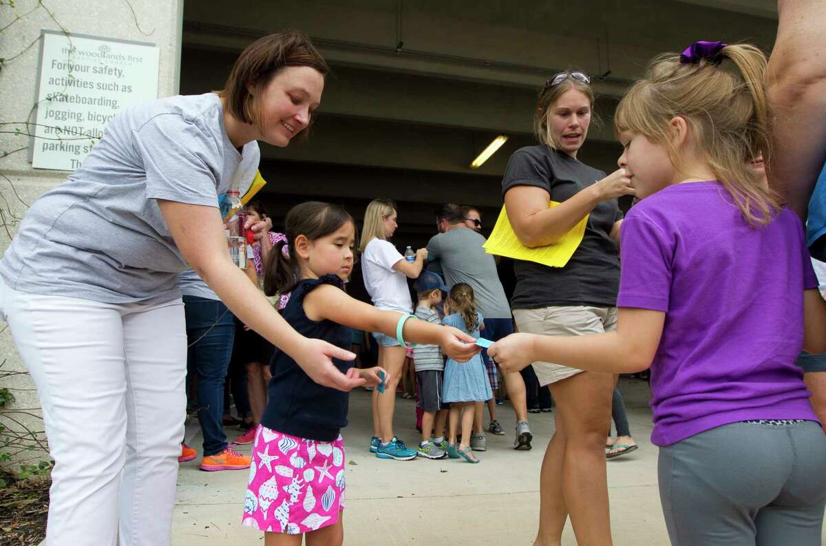Brittany Cabrera, left, helps her daughter Madelynn hand out a meal ticket to Caitlyn Abramson and her family as hundreds of residents affected by Hurricane Harvey were provided a free meal at Sam K. Hailey Elementary School, Aug. 30 in Spring.