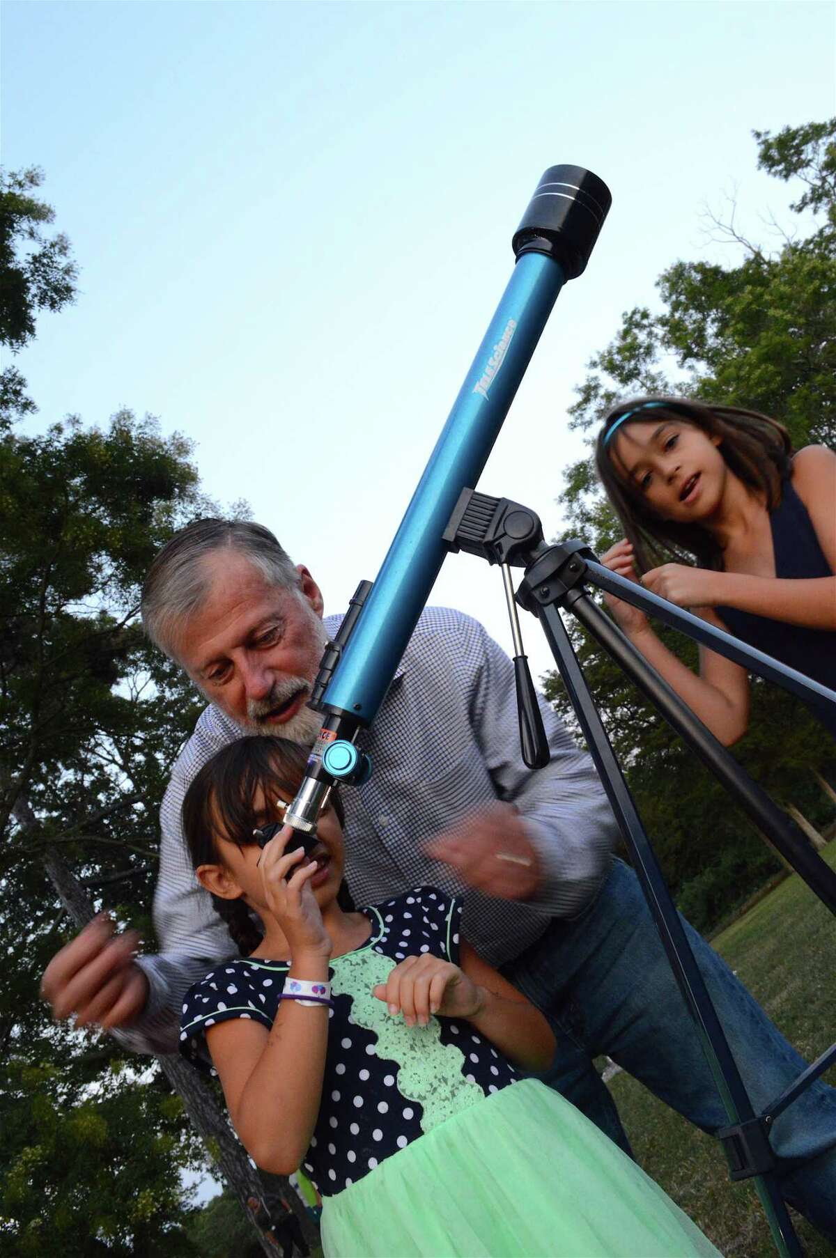 Mark Dam of Darien helps his granddaughter, Maya Dam, 6, of Westport, look at the moon through his telescope, as her sister Emma, 9, looks on at the Recreation Department's last Waveny Concert of the season, Wednesday, Aug. 30, 2017, at Waveny Park in New Canaan, Conn.