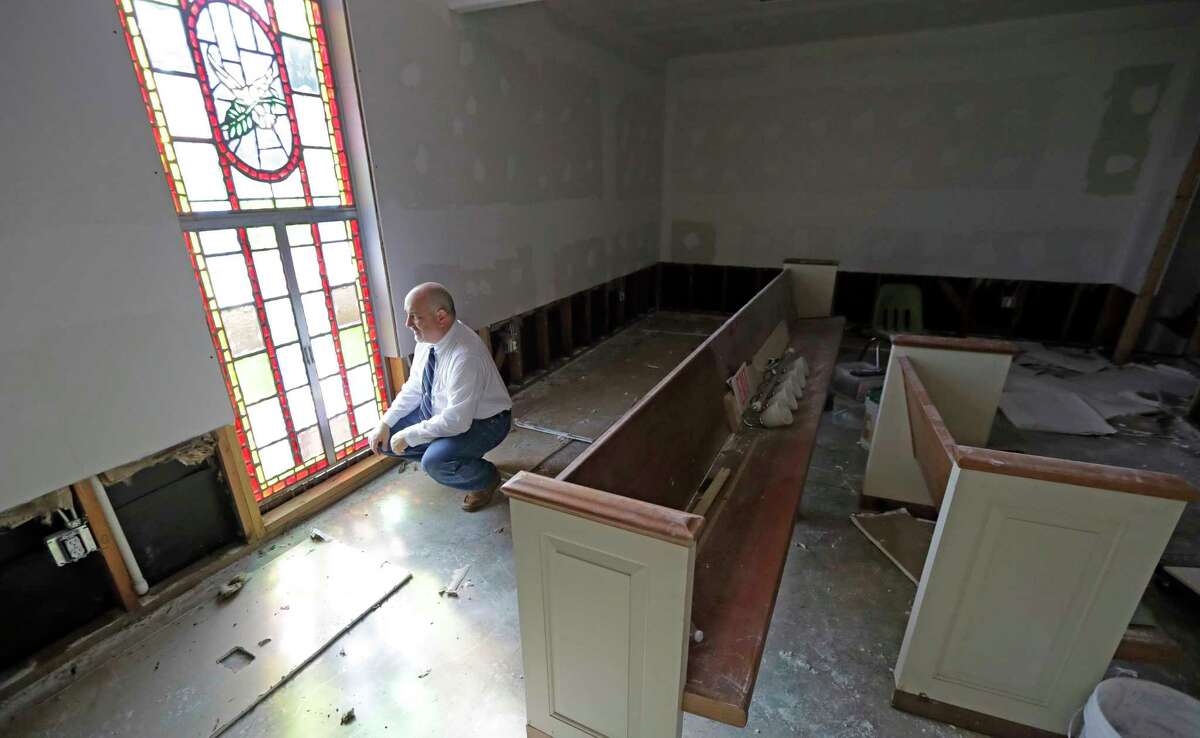 Pastor Jeffrey Willey kneels down inside the Christ United Church, which was flooded in the aftermath of Hurricane Harvey, on Sunday, Sept. 3, 2017, in Cypress, Texas. The church, which was flooded last year, had just recovered before Harvey caused more damage.
