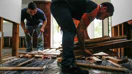 LC General Contractors employees Raul Gutierrez, left, and Misael Castillo, right, help to clear out a flooded home in Bellaire. The local contractors, accredited by the BBB, were remodeling the home when Harvey hit and transitioned from fixing the home to gutting it.