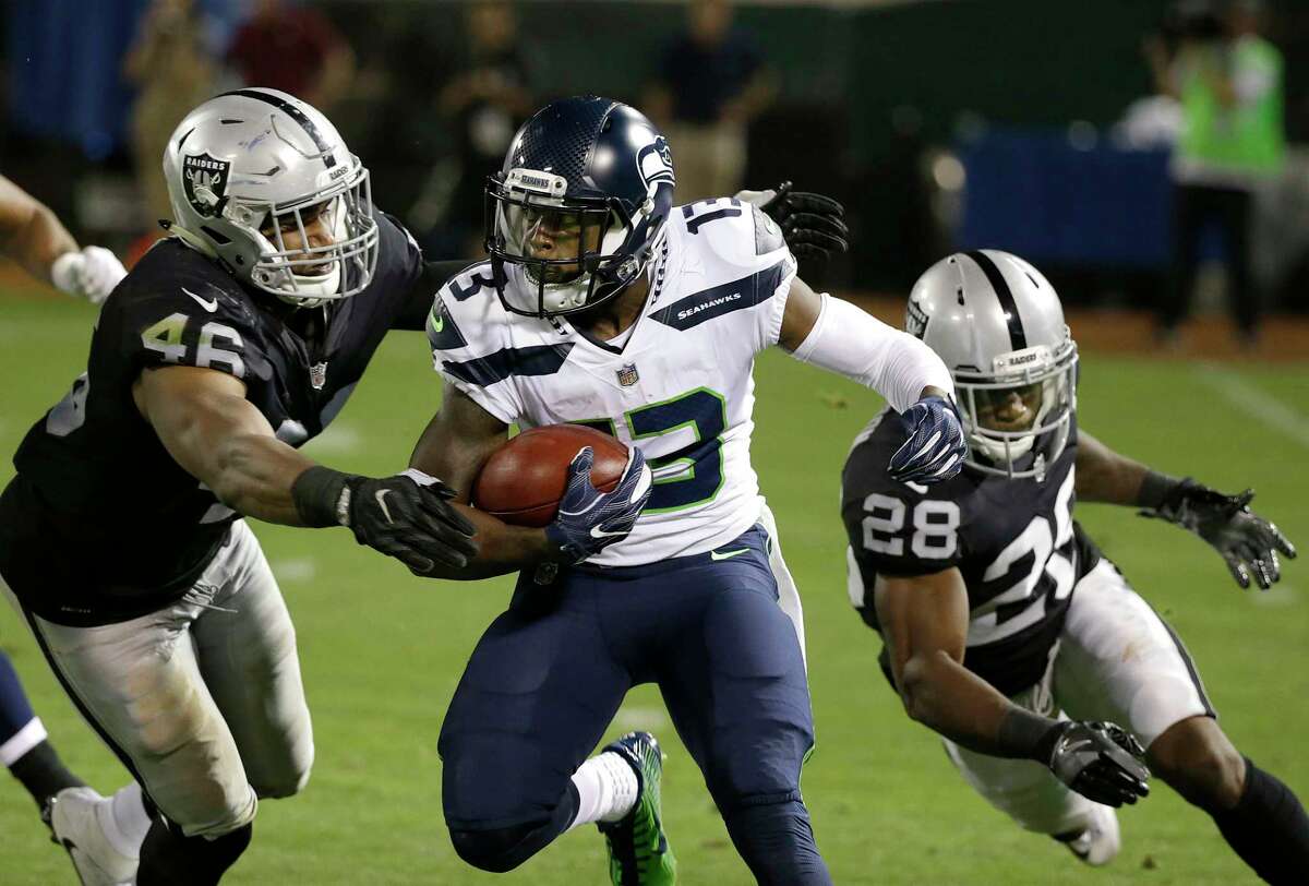 Seattle Seahawks' Cyril Grayson Jr. runs between Oakland Raiders linebacker LaTroy Lewis (46) and defensive back Marcus McWilson (28) during the first half of an NFL preseason football game in Oakland, Calif., Thursday, Aug. 31, 2017. (AP Photo/Eric Risberg)