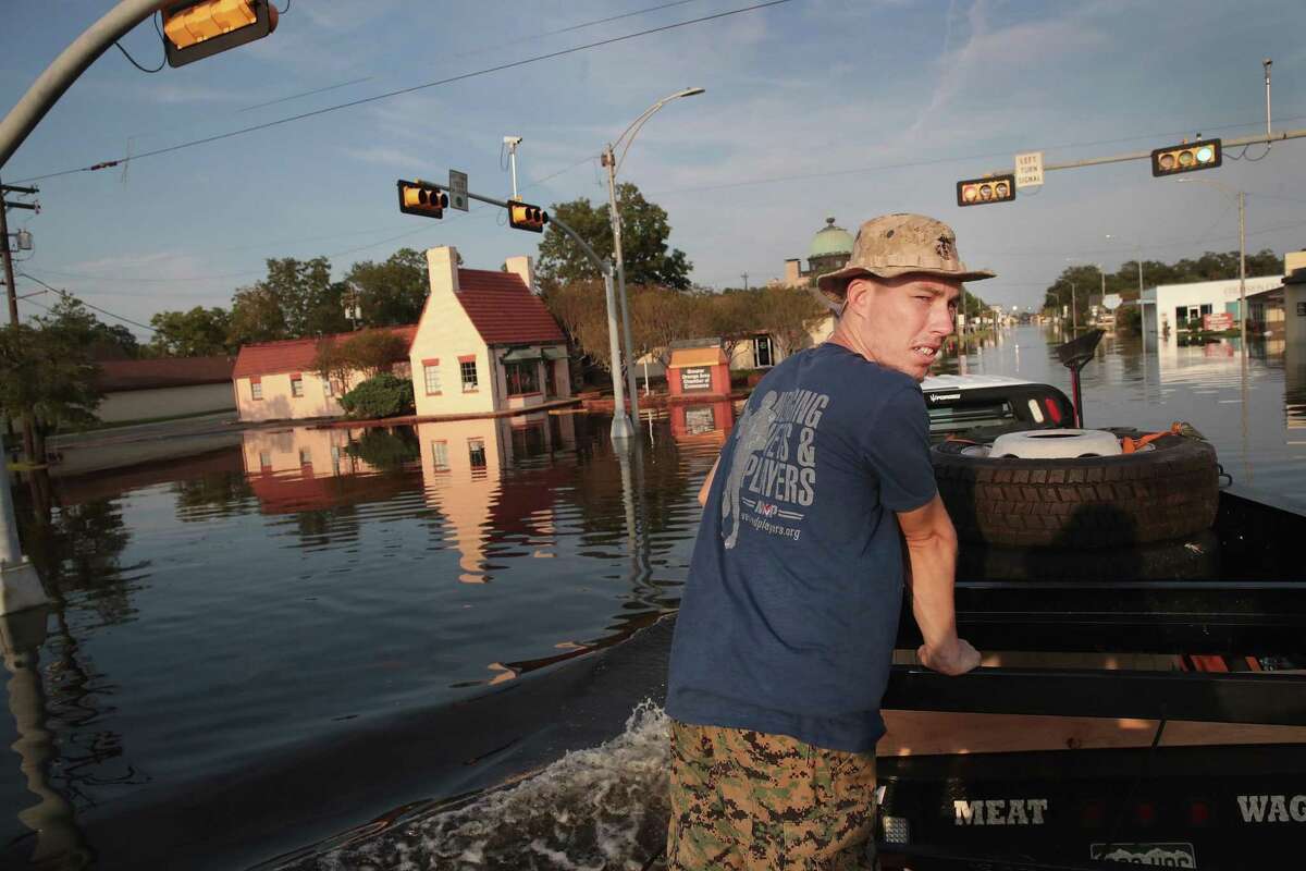 Chris Rogers, a volunteer with Merging Vets and Players, helps to distribute food and water to flood victims after the town was inundated when torrential rains pounded Southeast Texas following Hurricane and Tropical Storm Harvey causing widespread flooding on Sunday in Orange.