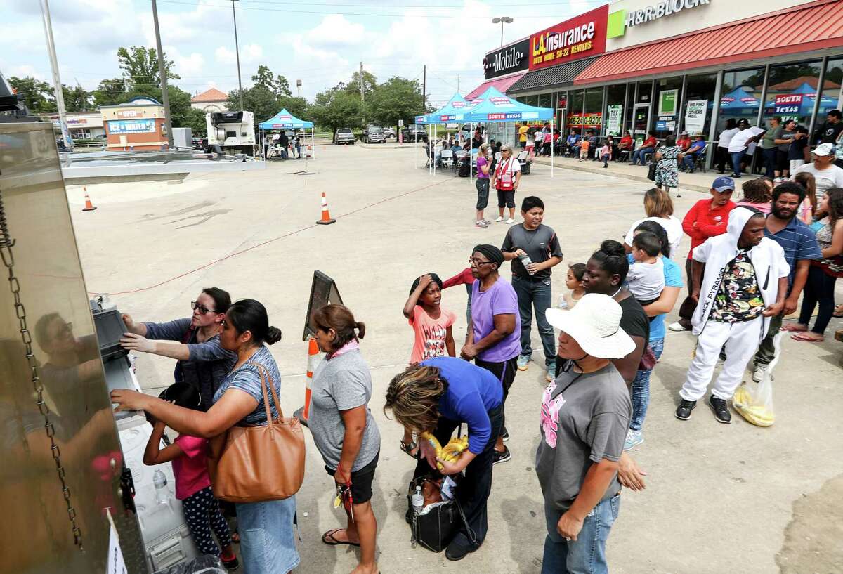 People line up for free barbecue prepared by "House of Hoops BBQ," in a parking lot at the corner of Mesa Drive and Tidwell Road, Tuesday, Sept. 5, 2017, in Houston. The grocery store at the corner flooded during Tropical Storm Harvey, leaving residents in the area without a grocery store nearby. ( Jon Shapley / Houston Chronicle )