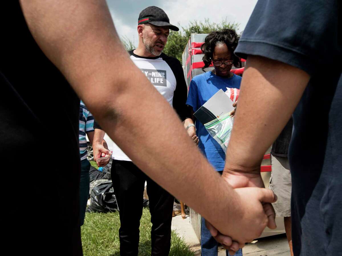 Juan Martinez, pastor of Get Wrapped Church, stands with Janice Dozier, whose home was flooded, as he gathers a group of his church members and victims of the flooding for a prayer on Tuesday, Sept. 5, 2017, in Spring.