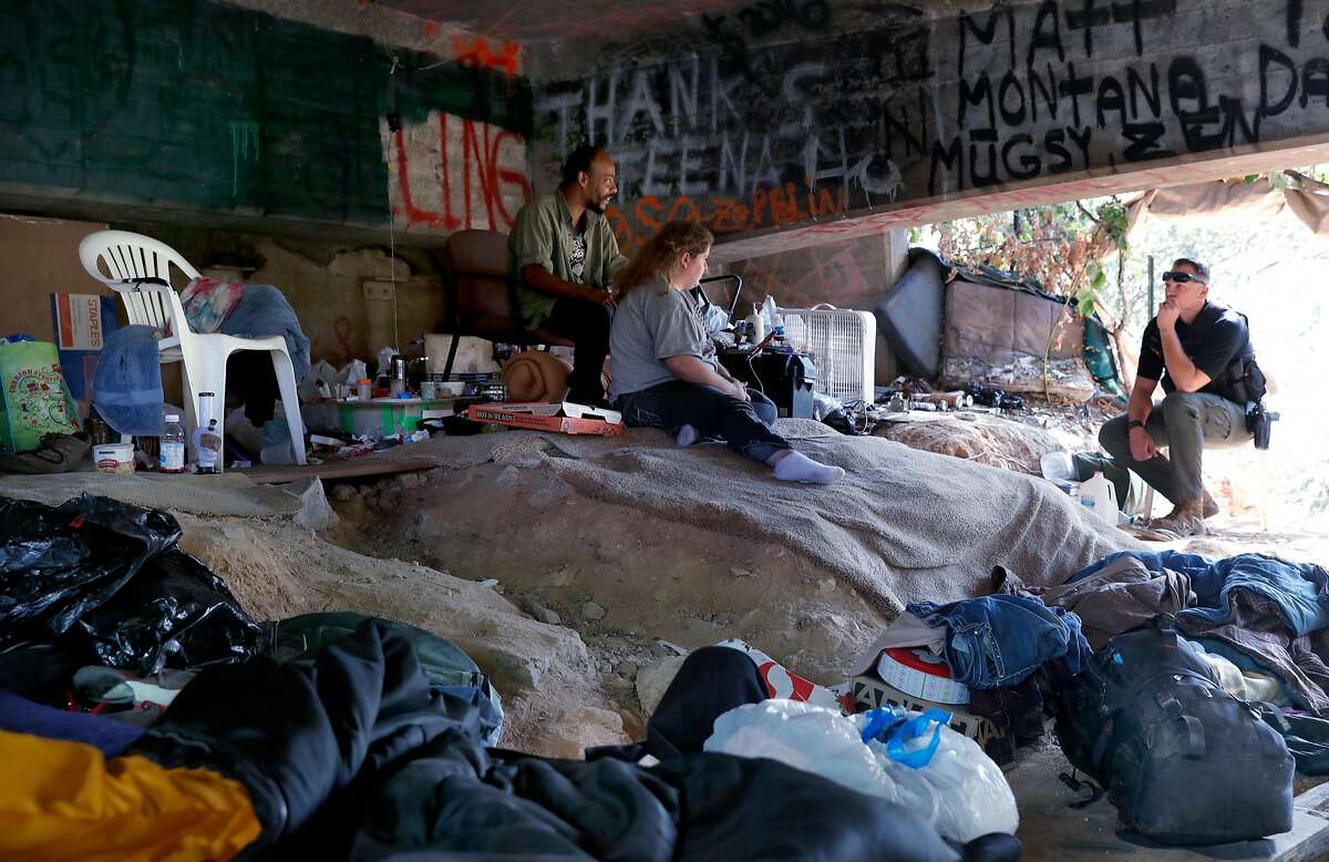 El Dorado County Deputy Blake Braafladt talks with Whitey and Sierra at their encampment under an abandoned highway 50 overpass on the outskirts of the city of in Placerville, Ca. on Tues. August 22, 2017. Braafladt is a member of the homeless outreach team.