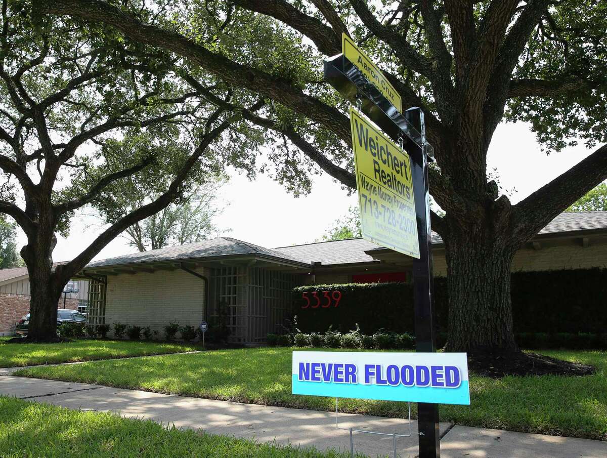 Real estate agent Aaron Cruz put up a "Never Flooded" sign on the lawn of a house that did not take on water in Meyerland after Tropical Storm Harvey flooded this area Wednesday, Sept. 6, 2017, in Houston. ( Yi-Chin Lee / Houston Chronicle )