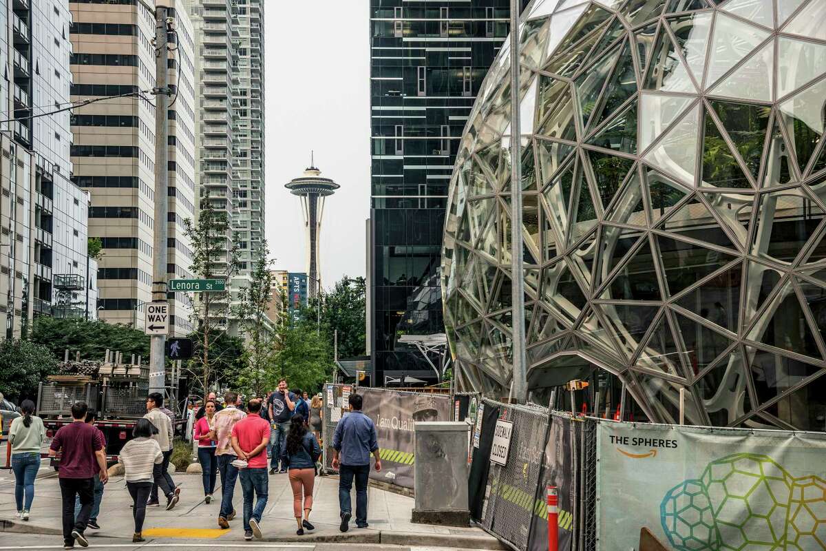 With the Space Needle observation tower visible in the distance, pedestrians walk past a recently built trio of geodesic domes that are part of the Seattle headquarters for Amazon, Sept. 7, 2017. The online retail giant said it was searching for a second headquarters in North America in 2017, a huge new development that would cost as much as $5 billion to build and run, and house as many as 50,000 employees. (Stuart Isett/The New York Times) ORG XMIT: XNYT221