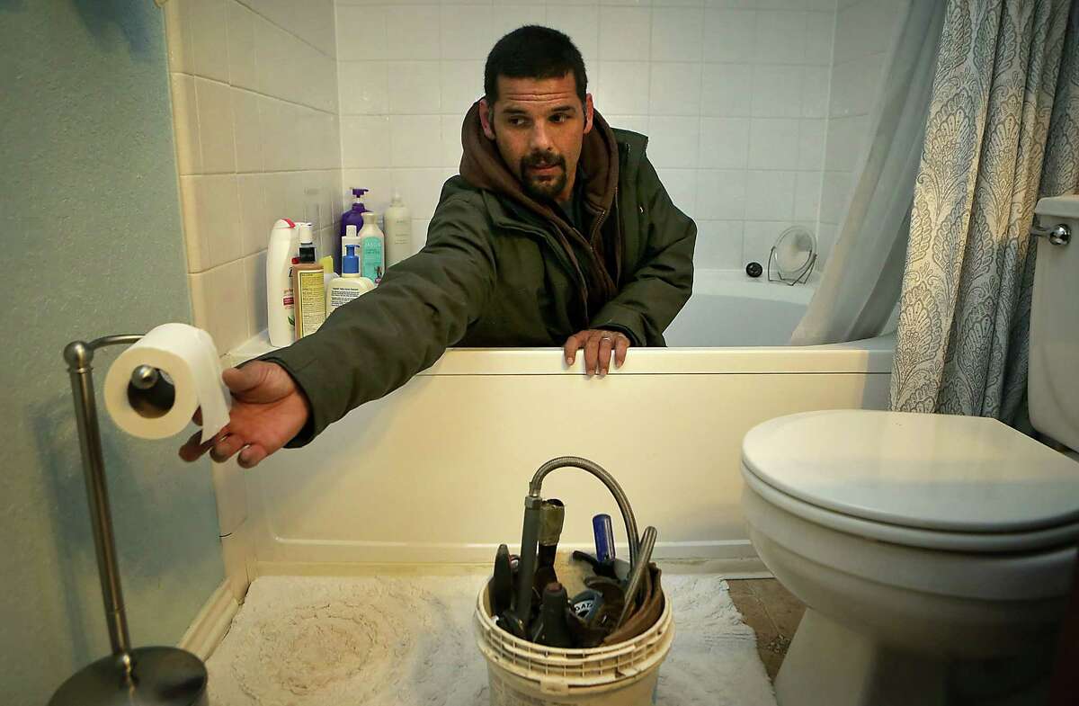 Anthony Cartagena, a San Antonio plumber, works cleaning out a bath tub drain in a client's home.