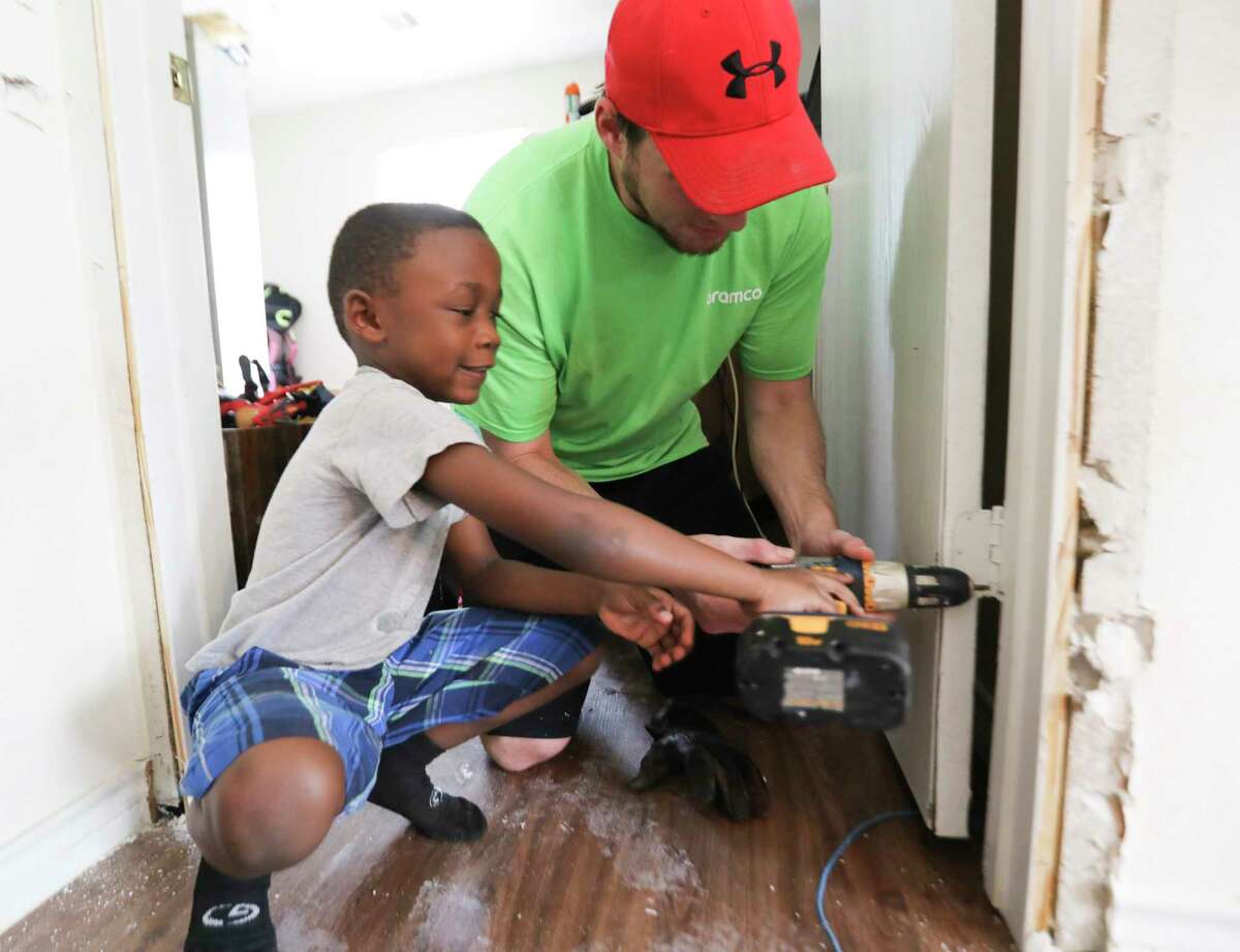 Jordan Pipkins, 6, helps volunteer Coy Custer remove screws ﻿from a door damaged in the storm.﻿