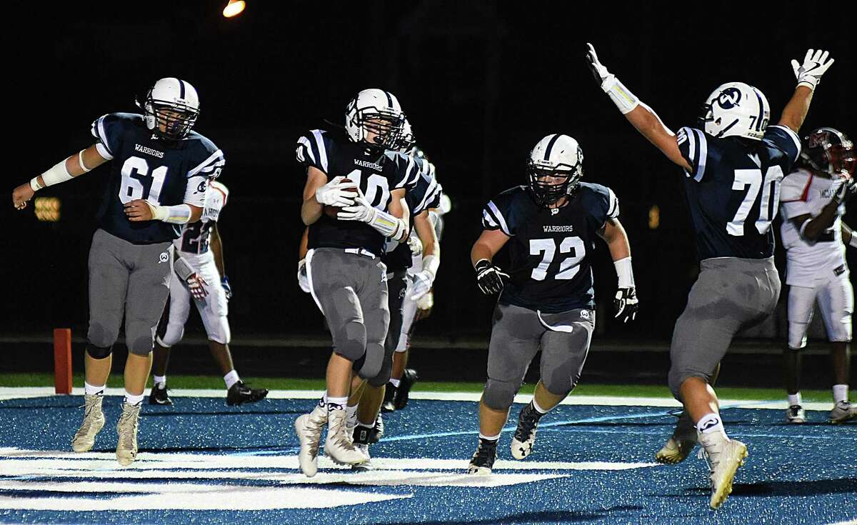 Wilton’s Kyle Phillips (10) scores his second of three touchdowns and celebrates with teammates during the Warriors’ 42-21 win over Brien McMahon on Friday at Fujitani Field in Wilton.