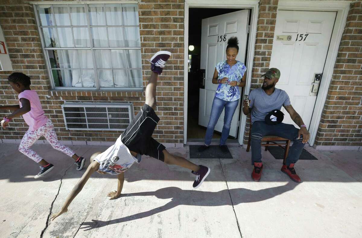 Natalie Spears, 8, and her brother, Christopher Spears, 9, play as their mother, Donna Spears, watches and Brandon Polson takes a video outside the Humble area motel Thursday, Sept. 7, 2017, where the family is staying after escaping their flooded apartment in the aftermath of Hurricane Harvey. The family has a hotel voucher from FEMA for temporary lodging through Sept. 25 and they're not sure where they'll go next. ( Melissa Phillip / Houston Chronicle )