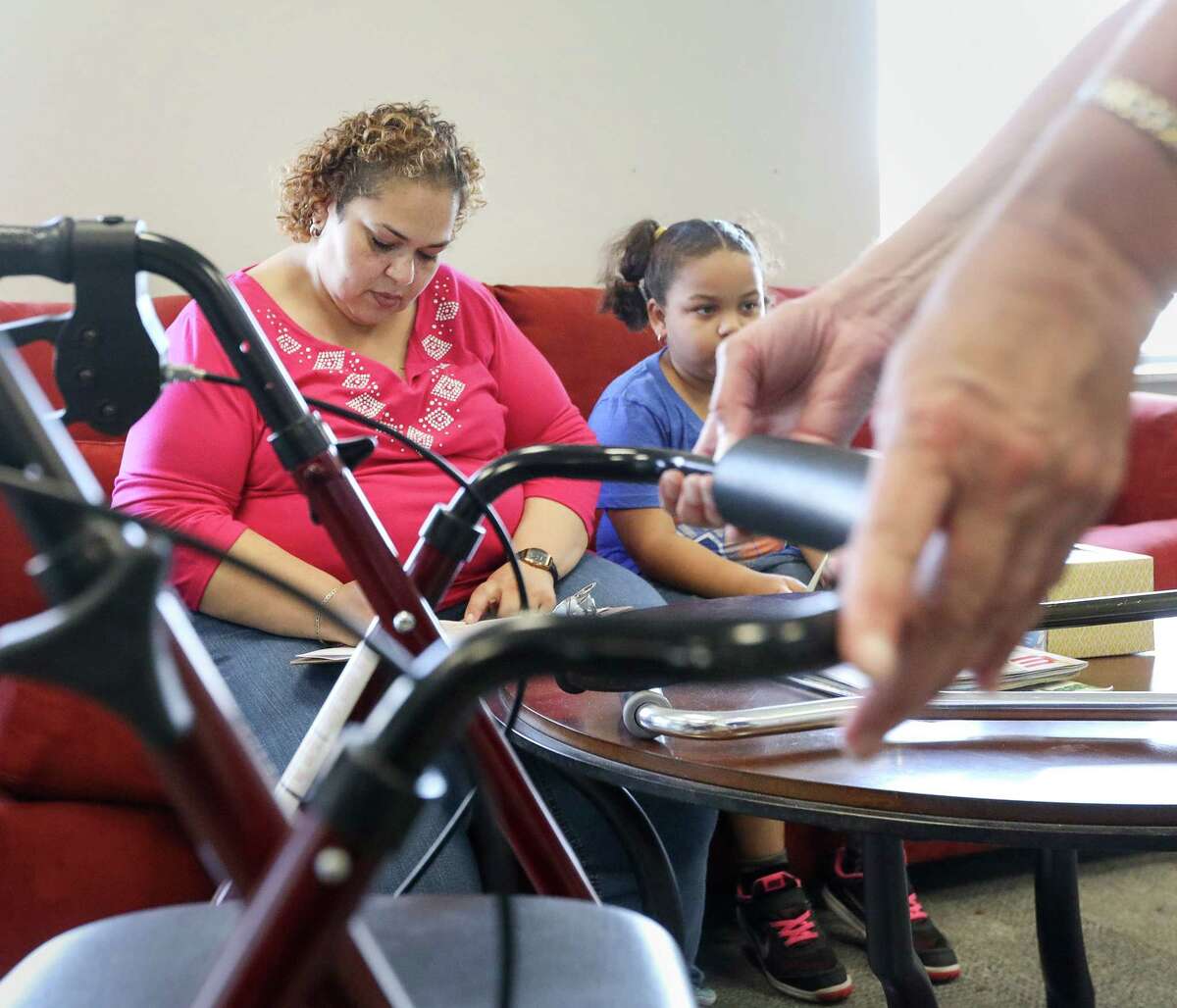 Patricia Morgan, left, and her daughter Danika, 7, fill out paperwork as Theresa Gregorio-Torres, an occupational therapist, explains the features of Morgan's new walker, during a medical supply donation event, Saturday, Sept. 9, 2017, in Houston. "I wasn't expecting all of this," Morgan said.