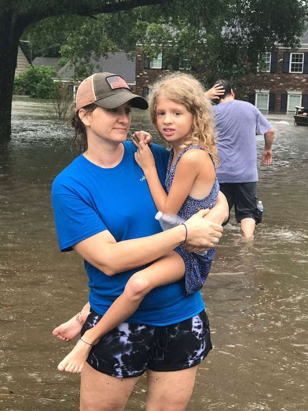 Laura Spaulding holds her daughter Lacey Spaulding while standing in the water left by Hurricane Harvey.