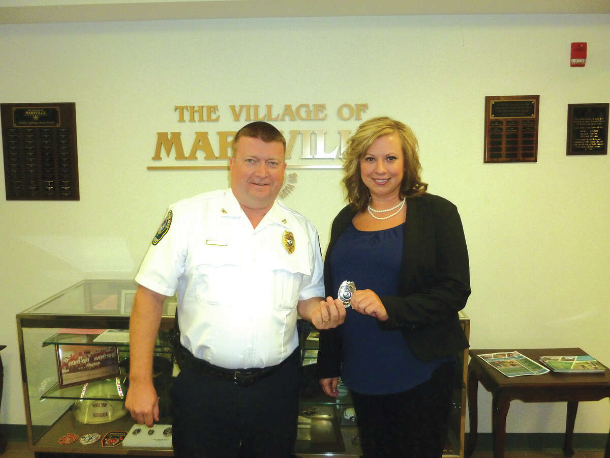 Maryville Police Chief Rob Carpenter presents a badge to newly-hired patrol officer Crissy Murphy at Wednesday's Maryville Village Board meeting.