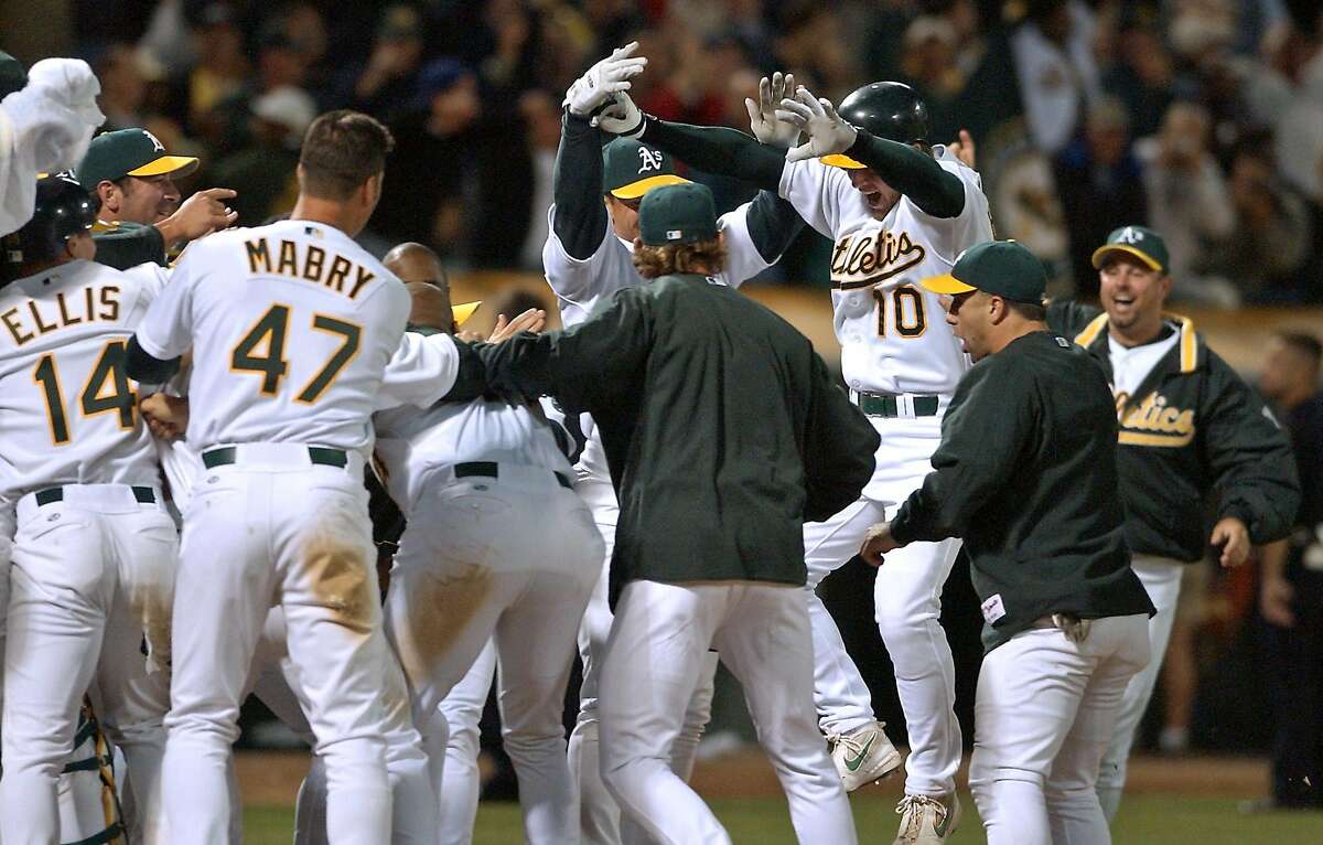 Oakland Athletics' Scott Hatteberg (10) jumps onto home plate and into the welcome of his teammates after hitting the game-winning home run off Kansas City Royals' Jason Grimsley in the ninth inning Wednesday, Sept. 4, 2002, in Oakland, Calif. The A's won 12-11 for their 20th consecutive victory, setting a new American League record. (AP Photo/Ben Margot)