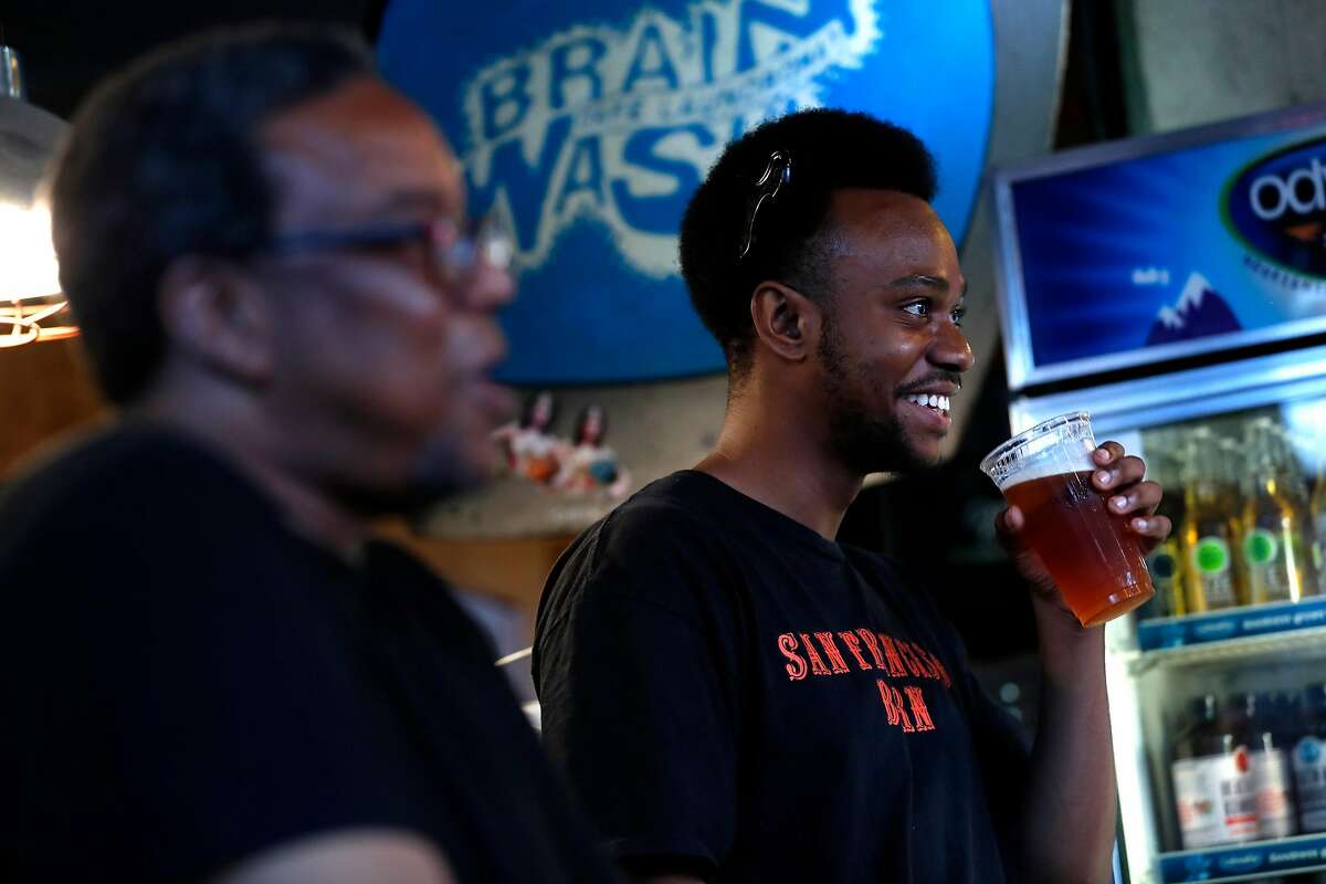 Mike Evans, Jr. (right) and Tony Sparks listen to a comedian during Magic Monday Open Mic at Brainwash Cafe in San Francisco, Calif., on Monday, September 4, 2017.