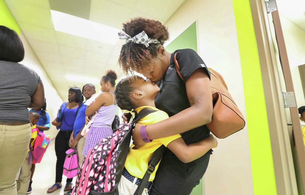 First-grader Jordain Hicks gives her mother Brittney Harvey a kiss before the start of school Monday at Codwell Elementary.