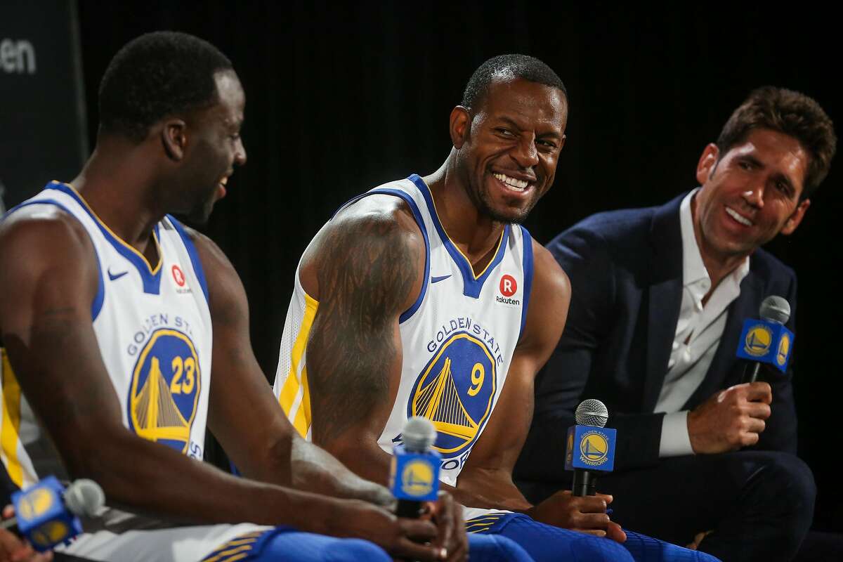 Draymond Green, Andre Iguodala and general manager Bob Myers laugh during a press conference.