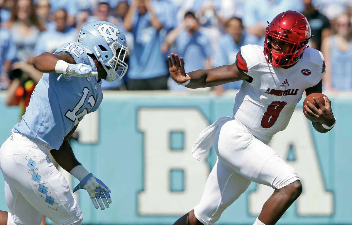 FILE - In this Sept. 9, 2017, file photo, Louisville quarterback Lamar Jackson (8) runs the ball as North Carolina's Tomon Fox (12) chases him during the first half of an NCAA college football game, in Chapel Hill, N.C. Jackson, the Heisman Trophy winner and All-American, leads the nation in total offense at 505 yards per game heading into a showdown with No. 3 Clemson. (AP Photo/Gerry Broome, File)